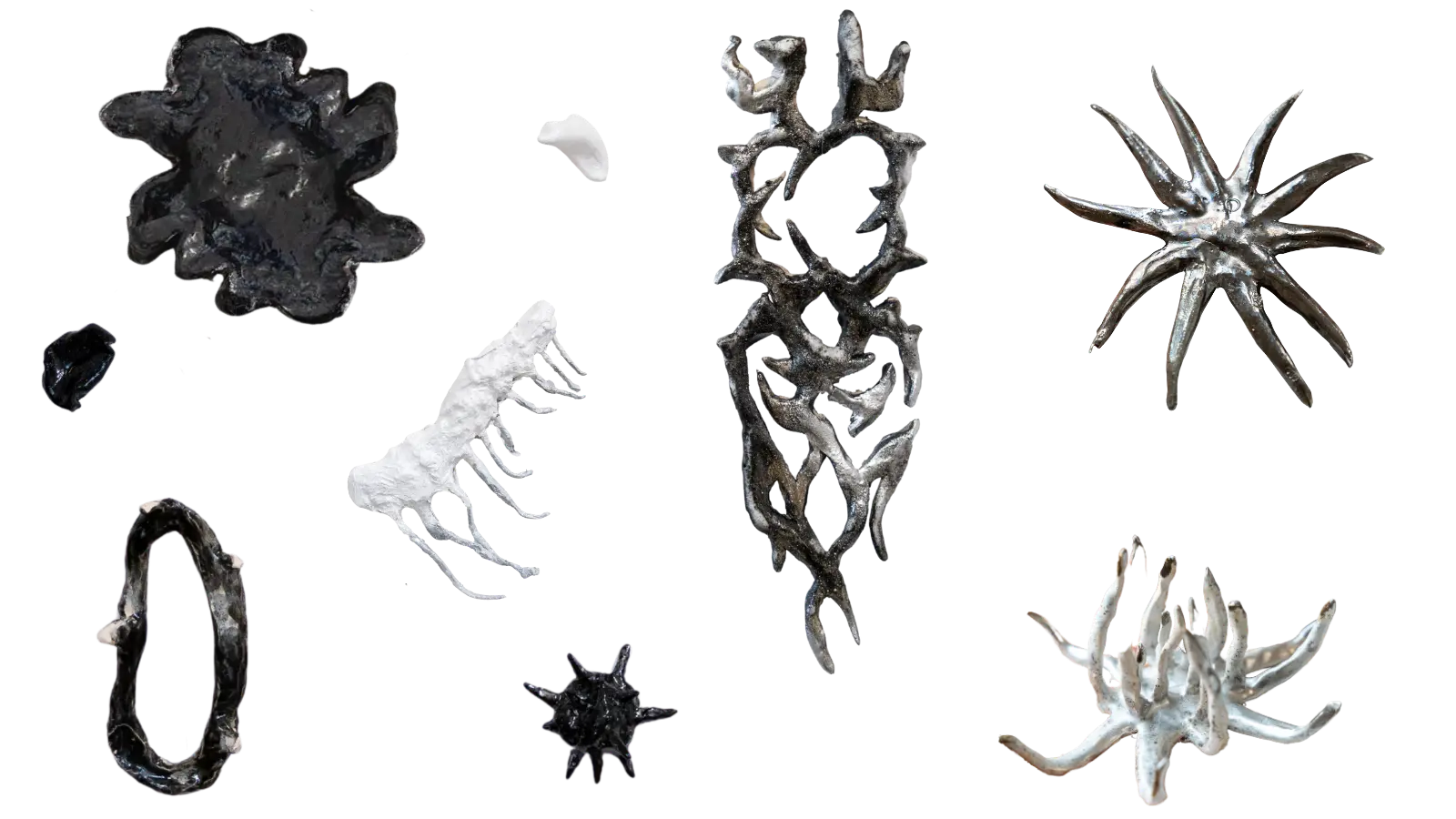 Collection of elongated, branching ceramic sculptures with irregular organic surfaces on a white background.