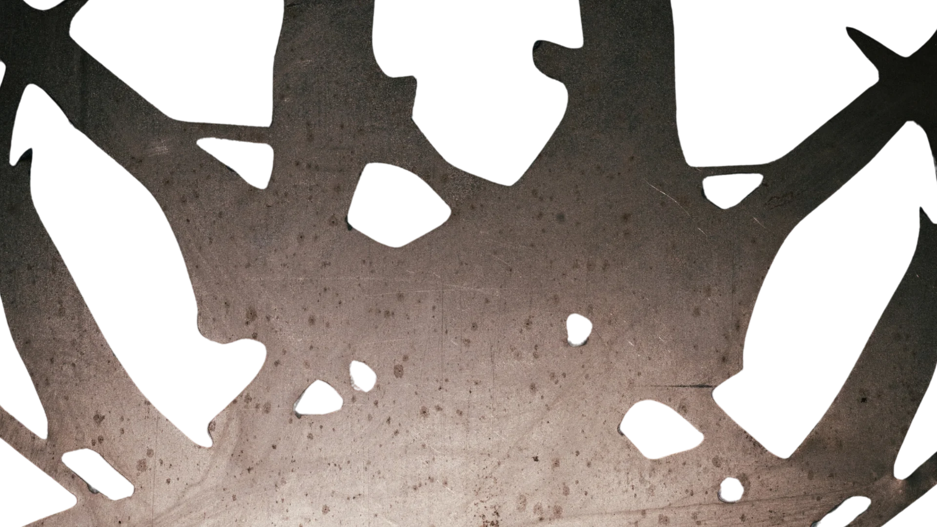 Close-up of a perforated steel silhouette with irregular openings and organic cut-out shapes.