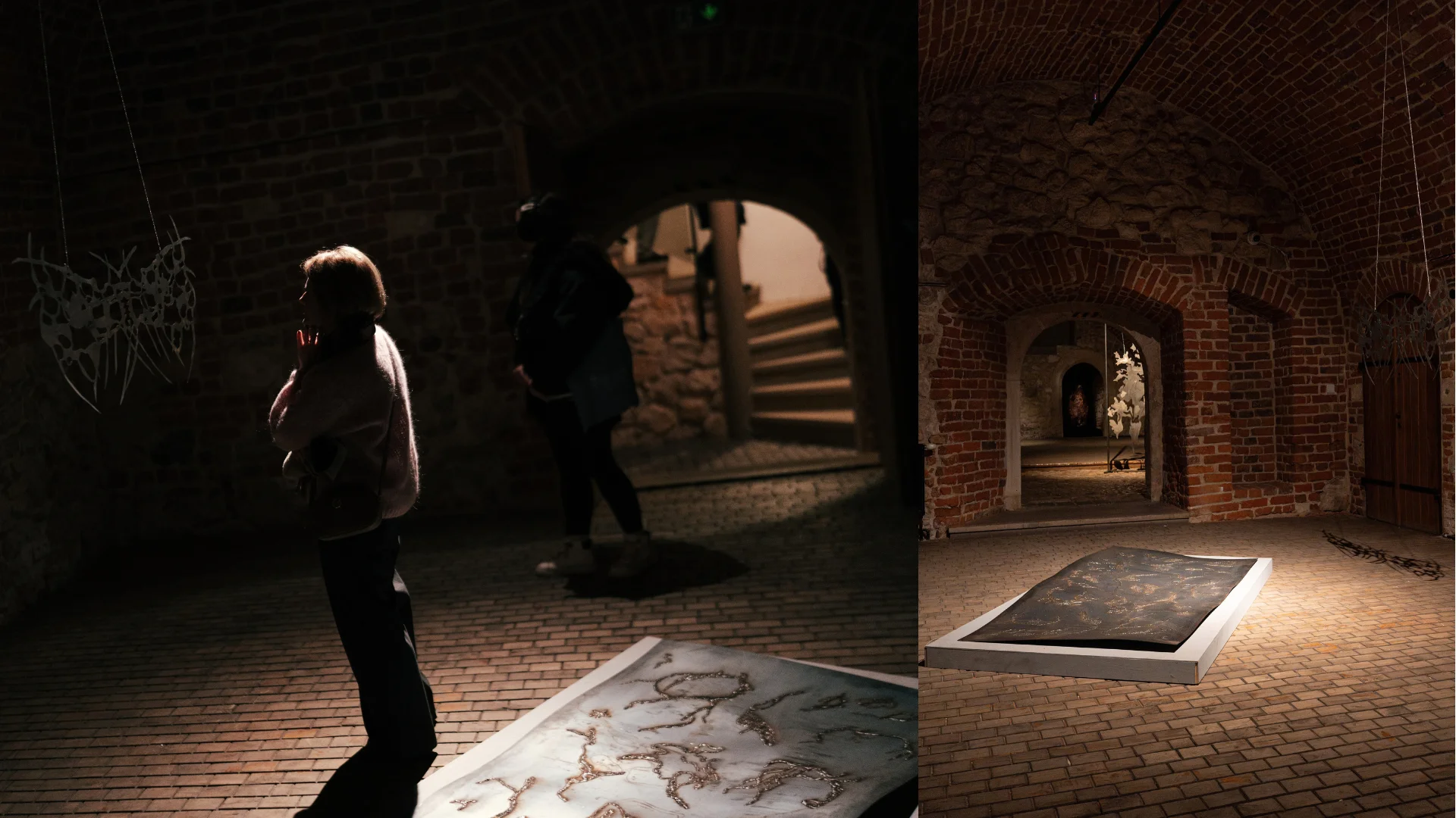 Dark brick exhibition interior with organic sculptures and visitors near an arched doorway.