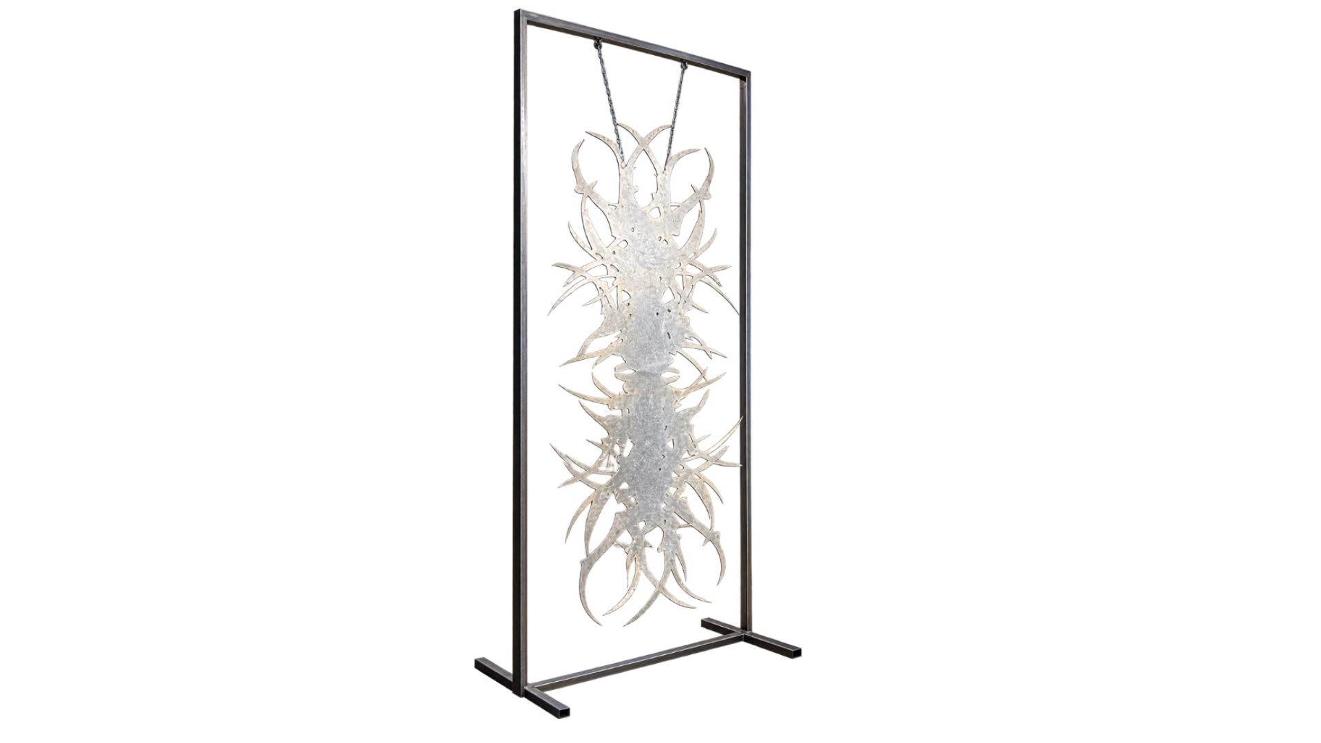 Tall rectangular metal frame containing a hanging abstract sculpture with irregular organic extensions.
